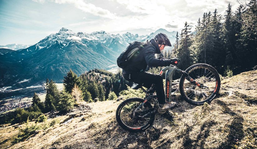 man rijd op haibike e-mtb berg op in de alpen