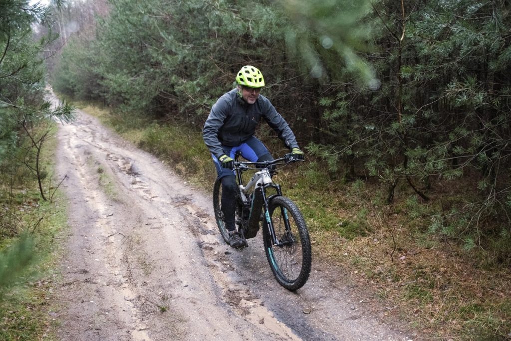mountainbiker met winterkleding fietst op zandpad