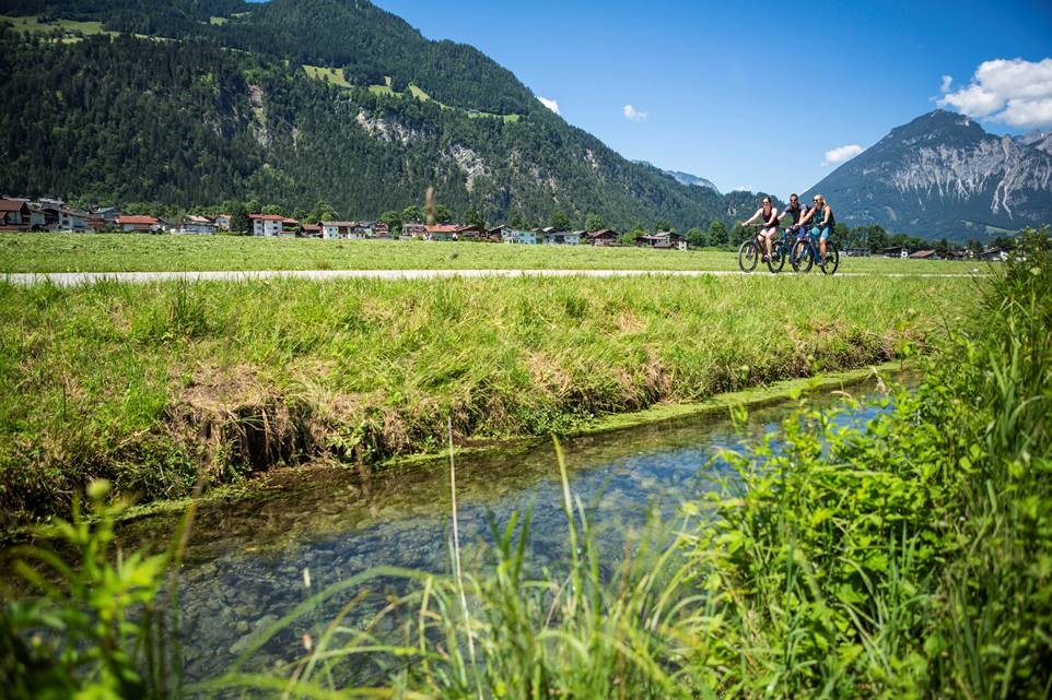 drie fietsers rijden door het Zillertal met bergen op de achtergrond