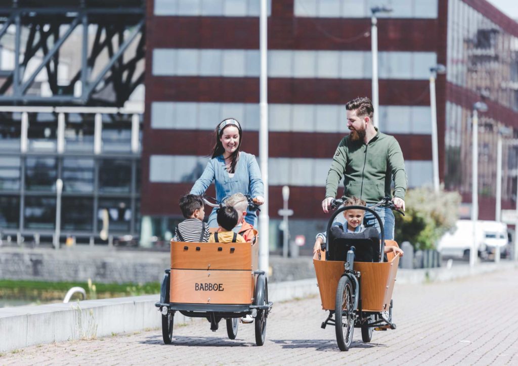 familie rijd samen op twee babboe bakfietsen