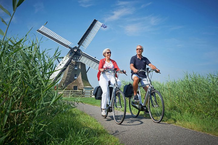 ouder stel fiets op e-bike voor een molen